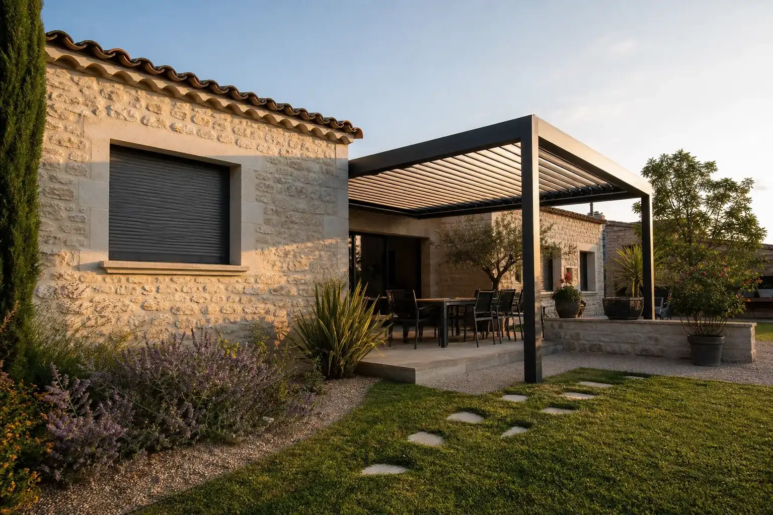 Façade de maison provençale avec volet roulant fermé et pergola aluminium sur une terrasse, lumière chaude de fin d’après-midi