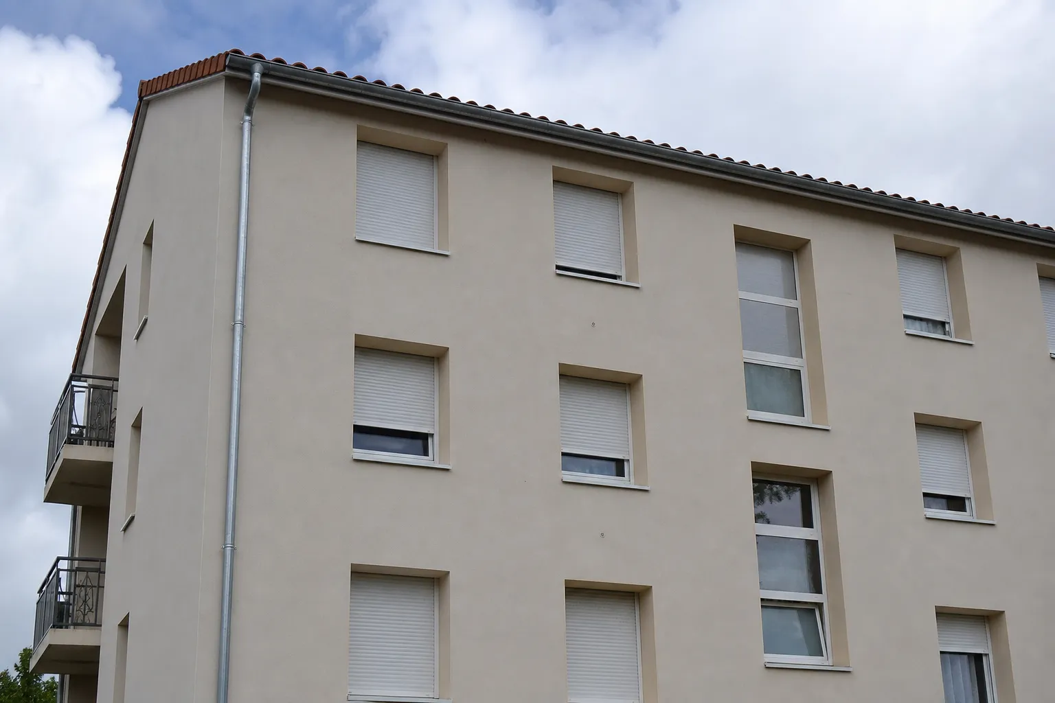Façade d’immeuble résidentiel avec plusieurs fenêtres équipées de volets roulants fermés à différentes hauteurs
