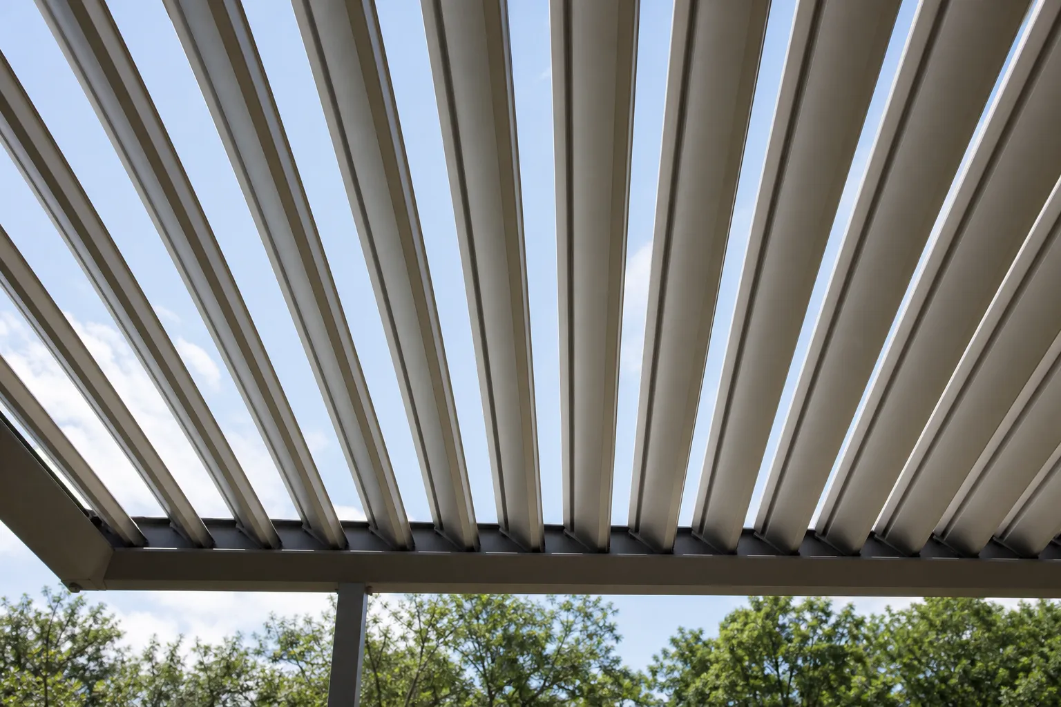 Pergola aluminium à lames orientables vue de dessous, lames partiellement ouvertes laissant passer la lumière